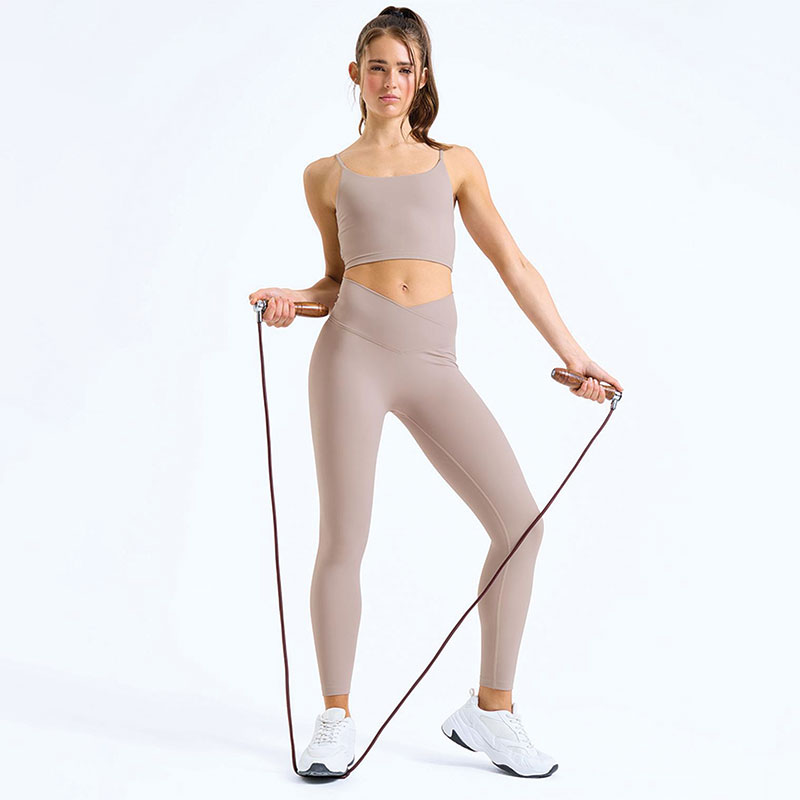 Woman wearing beige high-waisted sculpt leggings and sports bra, holding a skipping rope, full body activewear outfit.
